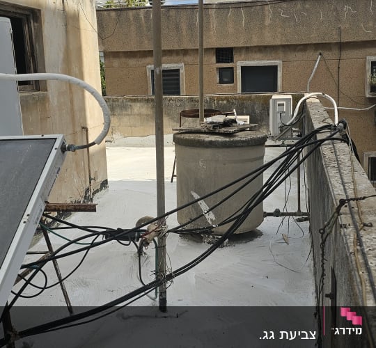 גג עם חומר איטום לבן, צינורות ומבנים סמוכים